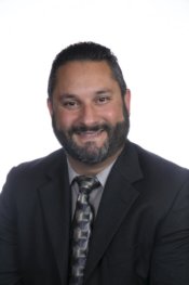 Professional Headshot of Frank F. Preveti in a black suit, with a powder blue shirt and a black patterned tie.